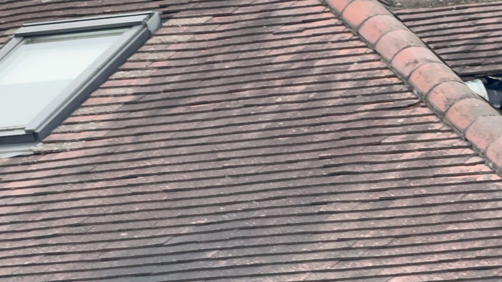 Close-up of a tiled roof with slipped tiles and a failing ridge