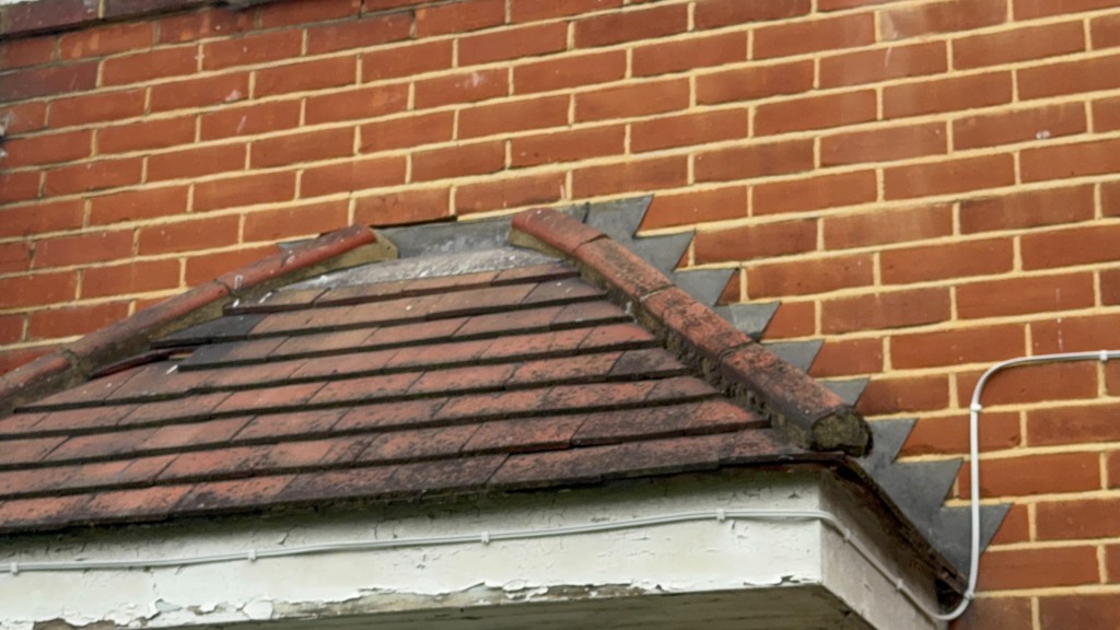 Close-up of brickwork where a bay roof meets the main wall