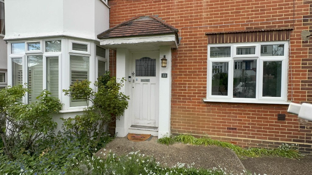 Front elevation of a brick house with bay windows and a porch